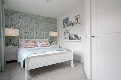 a bedroom with a white bed with two pink pillows at 3BDR House By Vista Stays Short Lets & Serviced Accommodation Glasgow Scotland With Driveway Parking and PS4 in Glasgow