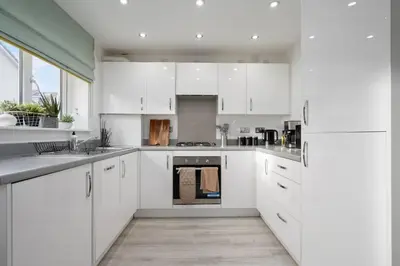 a white kitchen with white cabinets and appliances at 3BDR House By Vista Stays Short Lets & Serviced Accommodation Glasgow Scotland With Driveway Parking and PS4 in Glasgow