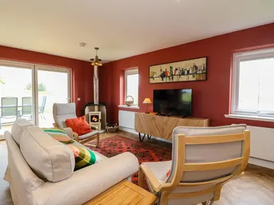 a living room with red walls and a tv at Tirlaggan Úr in Oban