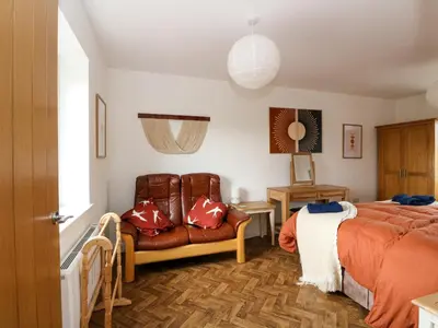 a bedroom with a bed and a leather couch at Tirlaggan Úr in Oban