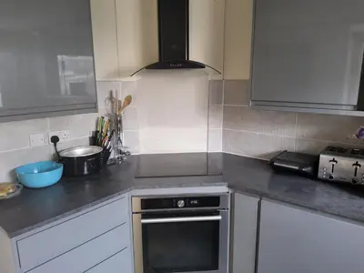 a kitchen with white cabinets and a stove top oven at Gadsby manor in Drumchapel