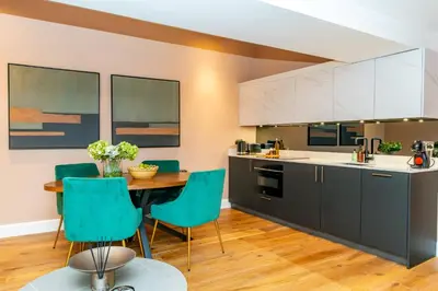 a kitchen with a table and blue chairs at Dragon Suites Luxury Apartments at 9 Albyn Place in Edinburgh