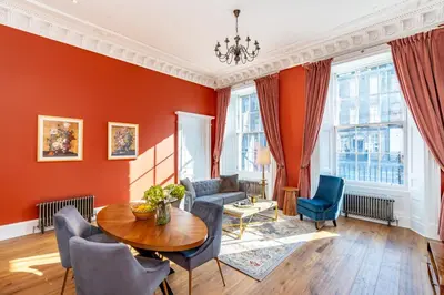 a living room with red walls and a table and chairs at Dragon Suites Luxury Apartments at 9 Albyn Place in Edinburgh