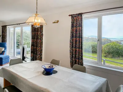 a dining room with a table and two large windows at Kiloran in Oban