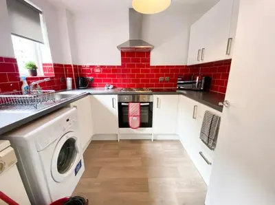 a kitchen with a washing machine and red tiles at Central two bedroom, Free private parking in Glasgow