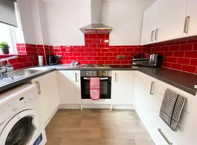 a kitchen with white cabinets and a red brick wall at Central two bedroom, Free private parking in Glasgow