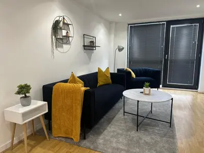 a living room with a blue couch and a table at Glasgow River Clyde Hydro Aprt in Glasgow
