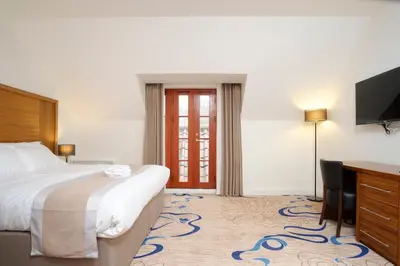 a hotel room with a bed and a desk and a television at Kelpies Hotel Falkirk in Falkirk