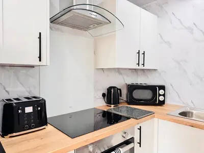 a kitchen with white cabinets and a black microwave at THE RESTING LION - Gourock Town Center Holiday Home Apartment in Gourock