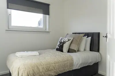 a bed with pillows and a window in a room at Dunbank Apartment in Clydebank