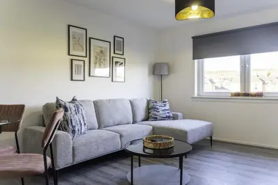 a living room with a couch and a table at Dunbank Apartment in Clydebank