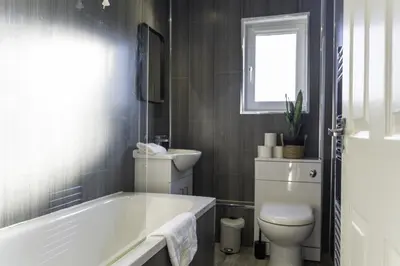 a bathroom with a tub and a toilet and a window at Dunbank Apartment in Clydebank