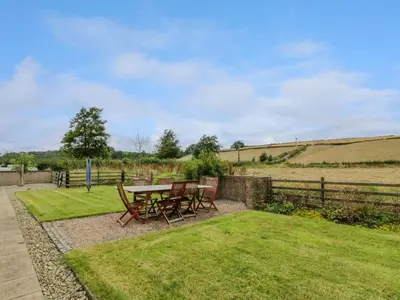 a patio with a table and chairs in the grass at The Stables at Daldorch in Mauchline