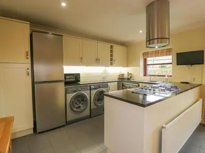 a kitchen with a stainless steel refrigerator and washing machines at The Stables at Daldorch in Mauchline