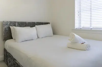 a bedroom with a bed with white pillows and a window at 3 BDR House By Caledonia Luxe Stays Short Lets & Serviced Accommodation Airdrie in Airdrie
