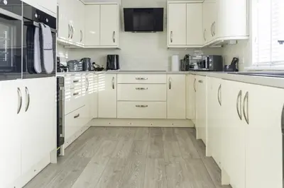 a kitchen with white cabinets and a wooden floor at 3 BDR House By Caledonia Luxe Stays Short Lets & Serviced Accommodation Airdrie in Airdrie