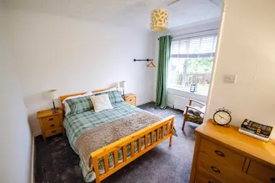 a bedroom with a bed and a desk and a window at Spacious 4-Bedroom House in Glenboig in Glenboig