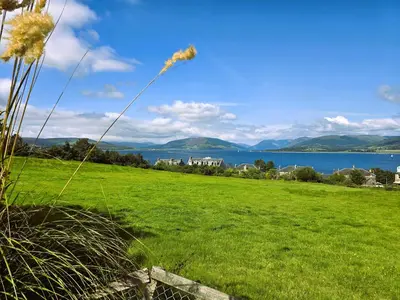 a kite flying in the sky over a green field at Bella Vista Manor - with elevated views over Rothesay & Loch Striven in Rothesay