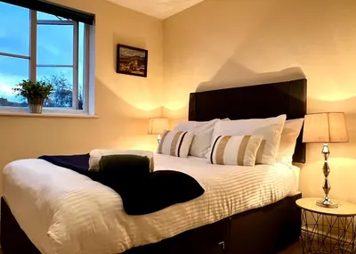 a bedroom with a large bed and a window at Charming, Cosy Escape with Quick Access to Glasgow in Paisley