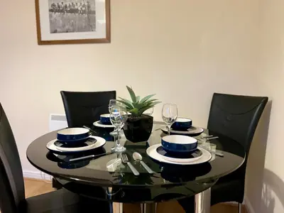 a dining room table with black chairs and a black table with glasses at Charming, Cosy Escape with Quick Access to Glasgow in Paisley