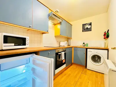 a kitchen with a washing machine and a microwave at Charming, Cosy Escape with Quick Access to Glasgow in Paisley