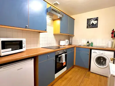 a kitchen with blue cabinets and a washer and dryer at Charming, Cosy Escape with Quick Access to Glasgow in Paisley