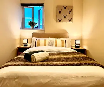 a bedroom with a large bed with two lamps at Charming, Cosy Escape with Quick Access to Glasgow in Paisley