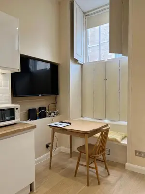 a small kitchen with a wooden table and a microwave at Edinburgh city centre 1Bed flat near Castle & Uni in Edinburgh