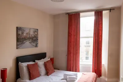a bedroom with a bed and a window with red curtains at 3 Bedroom Apartment with castle views in Edinburgh
