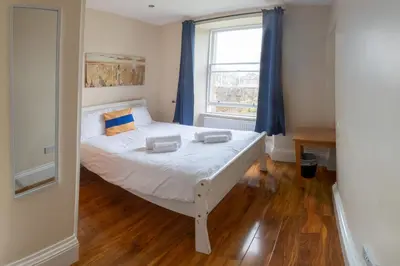 a bedroom with a white bed with blue curtains and a window at 3 Bedroom Apartment with castle views in Edinburgh