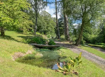 a bridge over a small pond in a park at Invercreran House in Appin