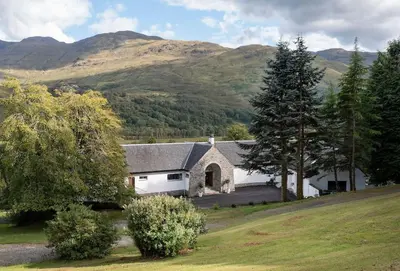a large white house with mountains in the background at Invercreran House in Appin