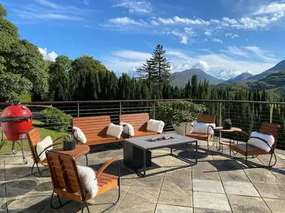 a patio with chairs and tables and a view of mountains at Invercreran House in Appin