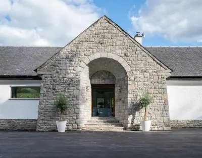 a stone building with an entrance with two potted plants at Invercreran House in Appin