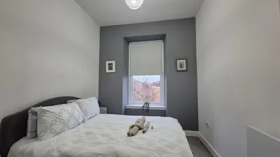 a teddy bear sitting on a bed in a bedroom at Bellshill Central Apartment in Bellshill