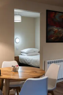 a dining room with a table and a bed at Taynuilt Inn Apartments in Taynuilt