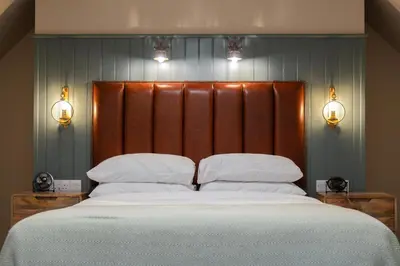 a bedroom with a large bed with a wooden headboard at Taynuilt Inn Apartments in Taynuilt