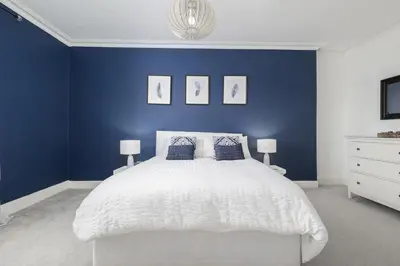 a blue bedroom with a white bed with blue walls at Extravagant 6 Bed Victorian Townhouse with Hot Tub in Glasgow