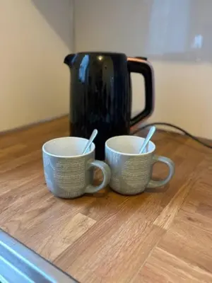 two cups sitting on a table with a coffee pot at Modern apartment in Stenhousemuir in Stenhousemuir