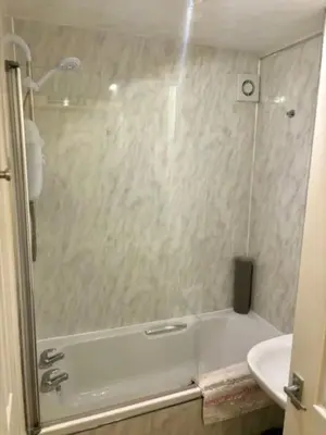a bathroom with a shower and a tub and a sink at Modern apartment in Stenhousemuir in Stenhousemuir