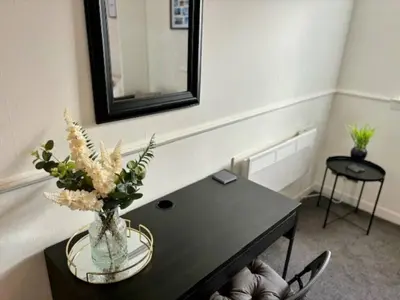 a room with a table with a vase of flowers on it at Modern apartment in Stenhousemuir in Stenhousemuir