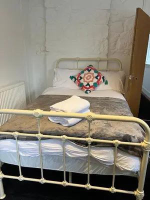 a bed with a metal frame and a pillow on it at Gogarstone Cottage in EDI