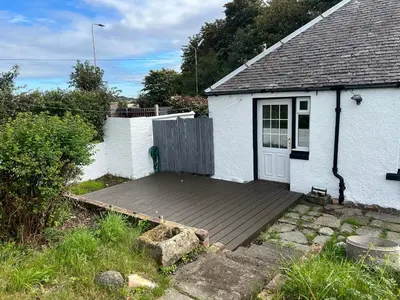 a wooden deck in front of a white house at Gogarstone Cottage in EDI