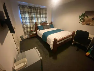 a bedroom with a bed and a chair and a window at Harbury Lodge in Scotstoun West Station