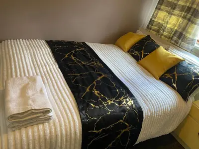 a bed with black and white sheets and yellow pillows at Harbury Lodge in Scotstoun West Station