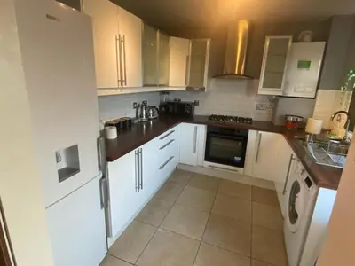 a kitchen with white cabinets and white appliances at Harbury Lodge in Scotstoun West Station