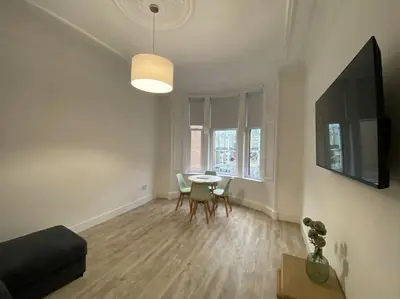 a living room with a table and a tv at 1 Smithhills Sleeps 5 Central and Spacious in Paisley