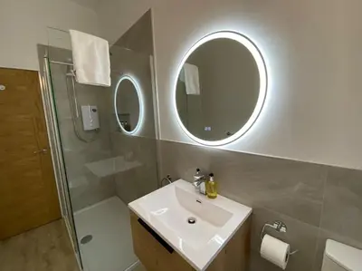 a bathroom with a sink and a shower and a mirror at 1 Smithhills Sleeps 5 Central and Spacious in Paisley