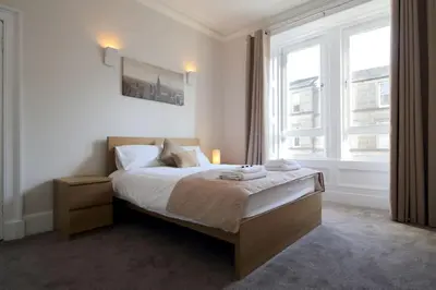 a bedroom with a bed and a large window at Modern City Centre Apartment in Central Hub in Edinburgh