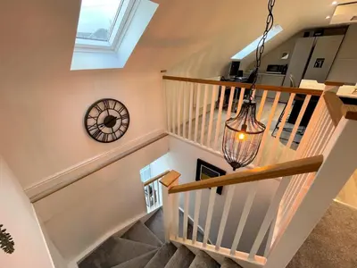 a staircase with a clock and a chandelier at Stunning Cosy Cottage in Historic Moffat - Pass the Keys in Moffat